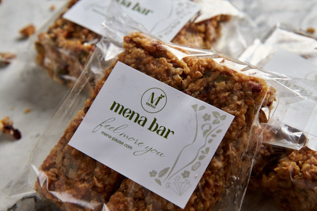 Mena bar plant-based snack bar in clear packaging on a stone surface.