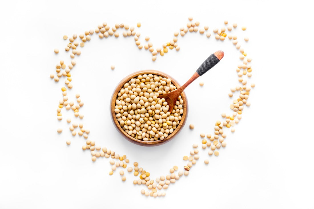 Soybeans arranged in a heart shape around a wooden bowl with a spoon, representing phytoestrogens.