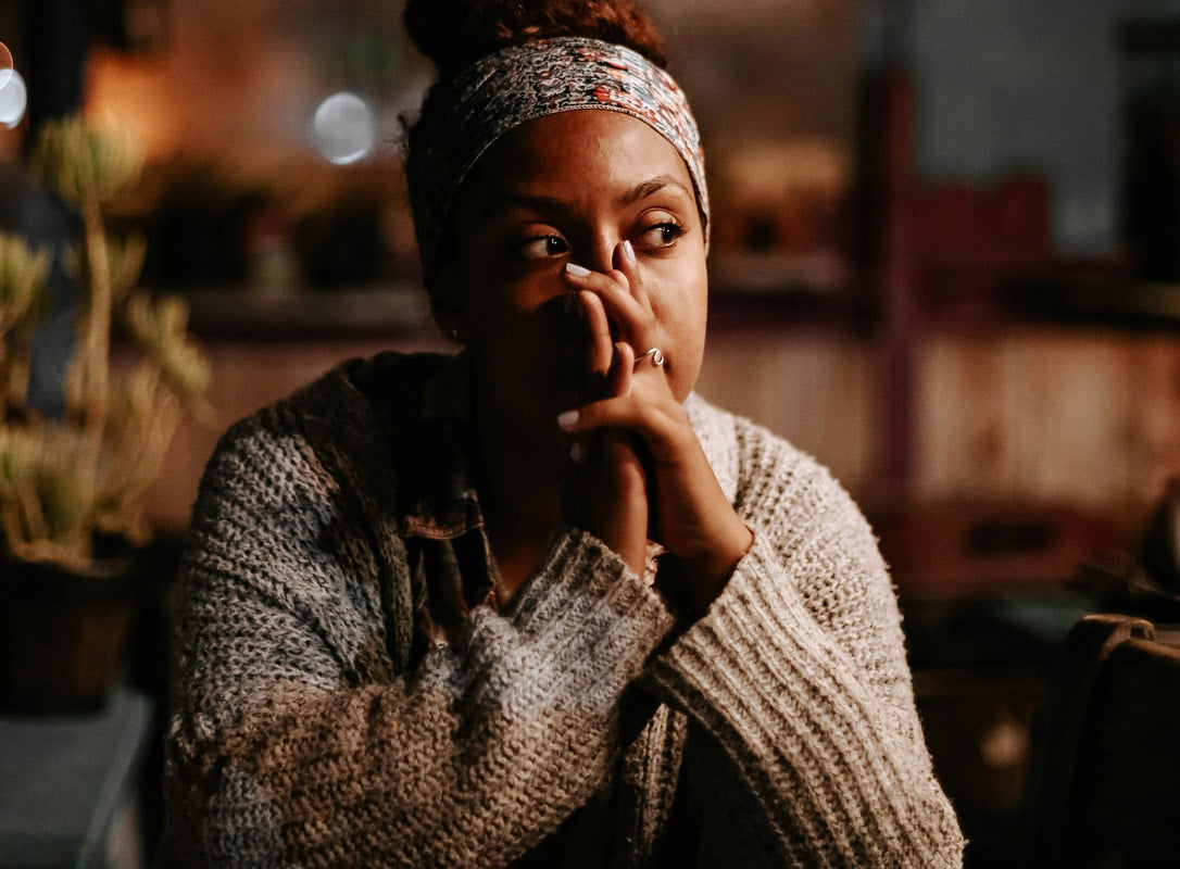 A pensive woman resting her chin on her hands, reflecting on perimenopause symptoms.