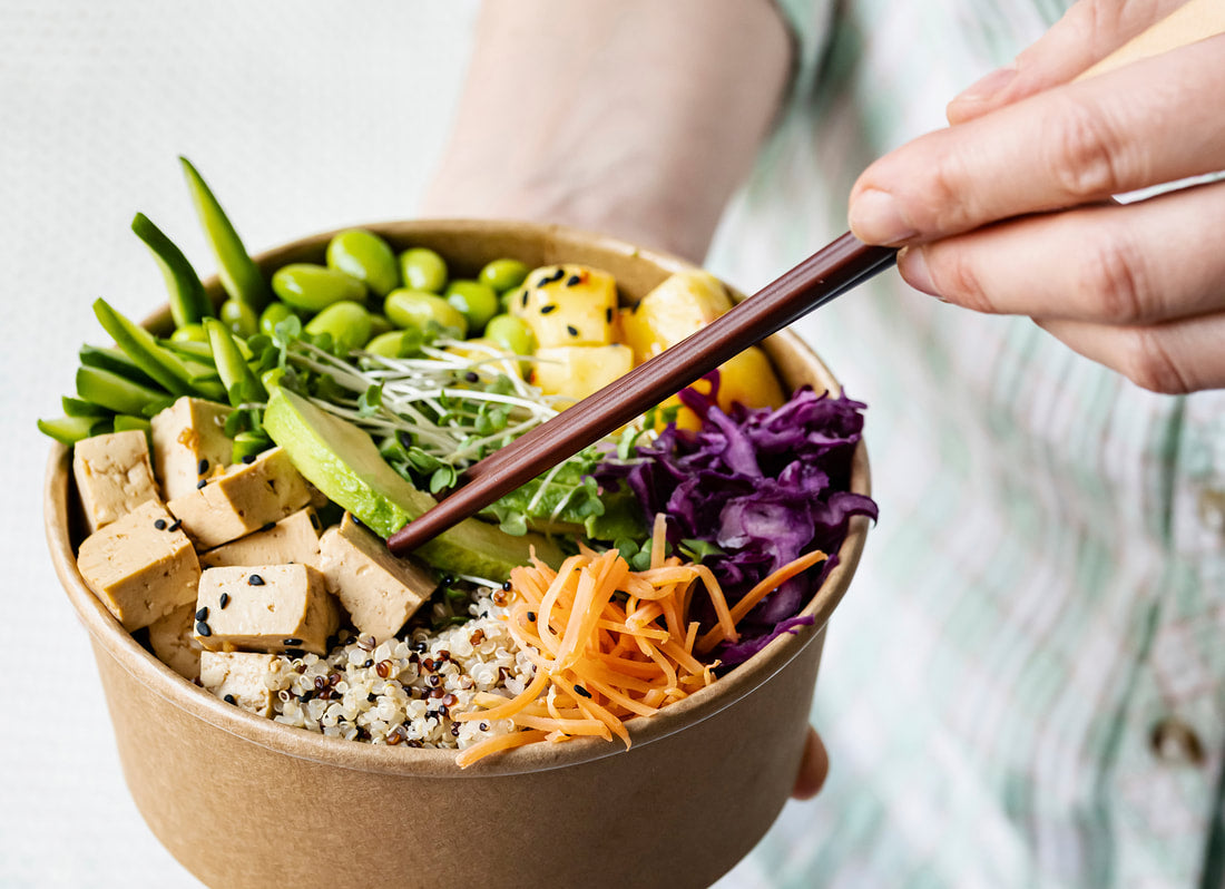 A colorful plant-based Buddha bowl with tofu, edamame, quinoa, and shredded vegetables.