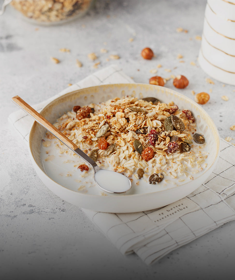 A bowl of healthy muesli with oats, seeds, and dried fruit in milk on a linen napkin.